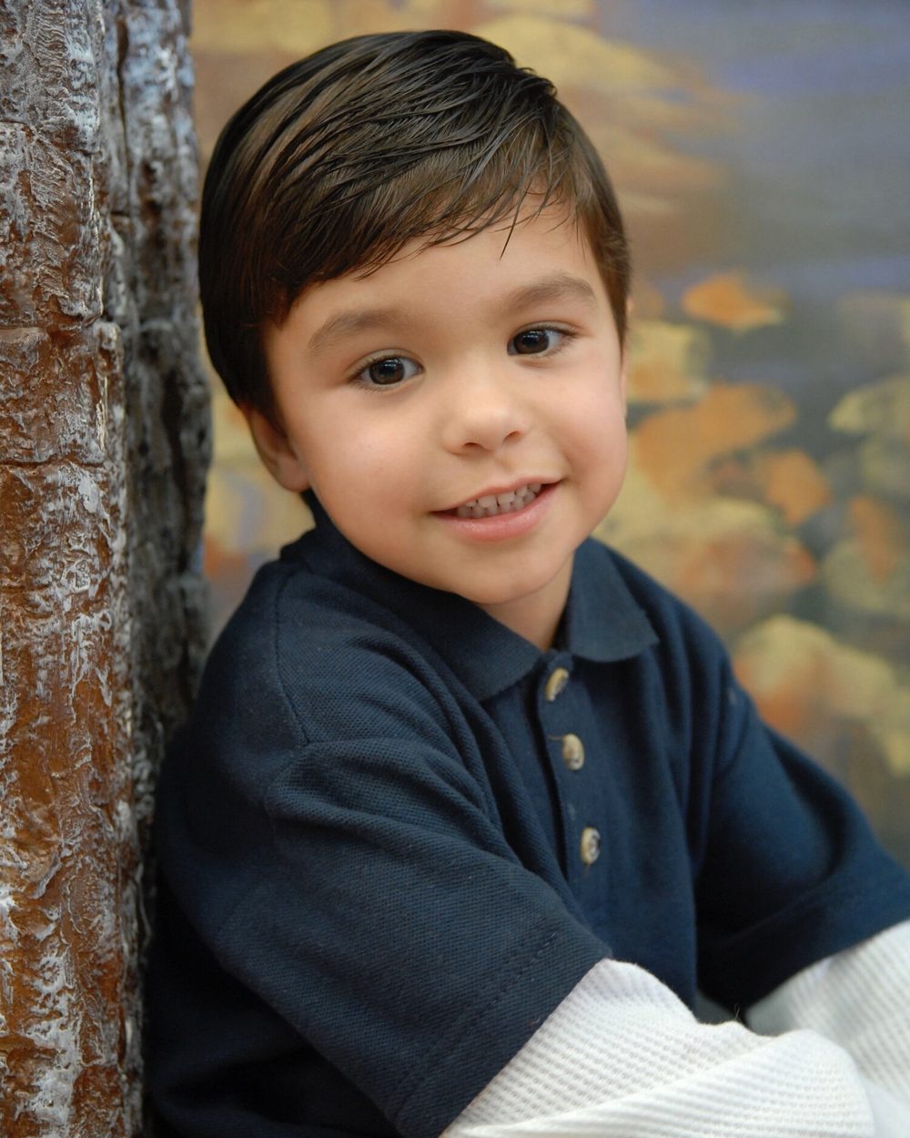 Boy in a navy polo smiling for his school portrait