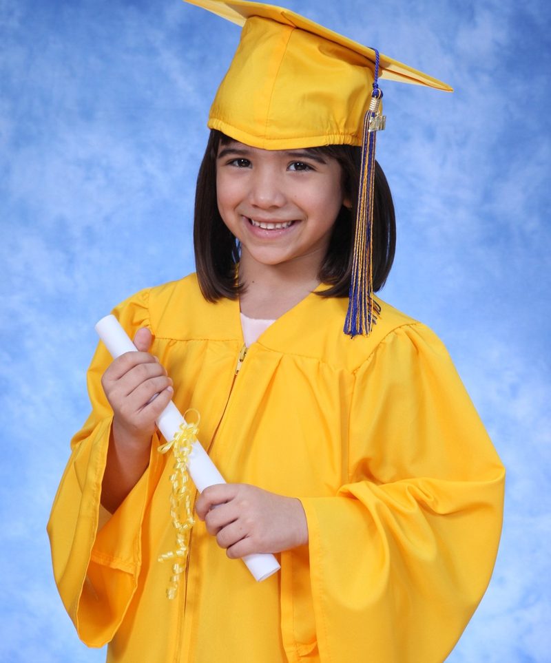 Graduate in a yellow cap and gown holding a diploma