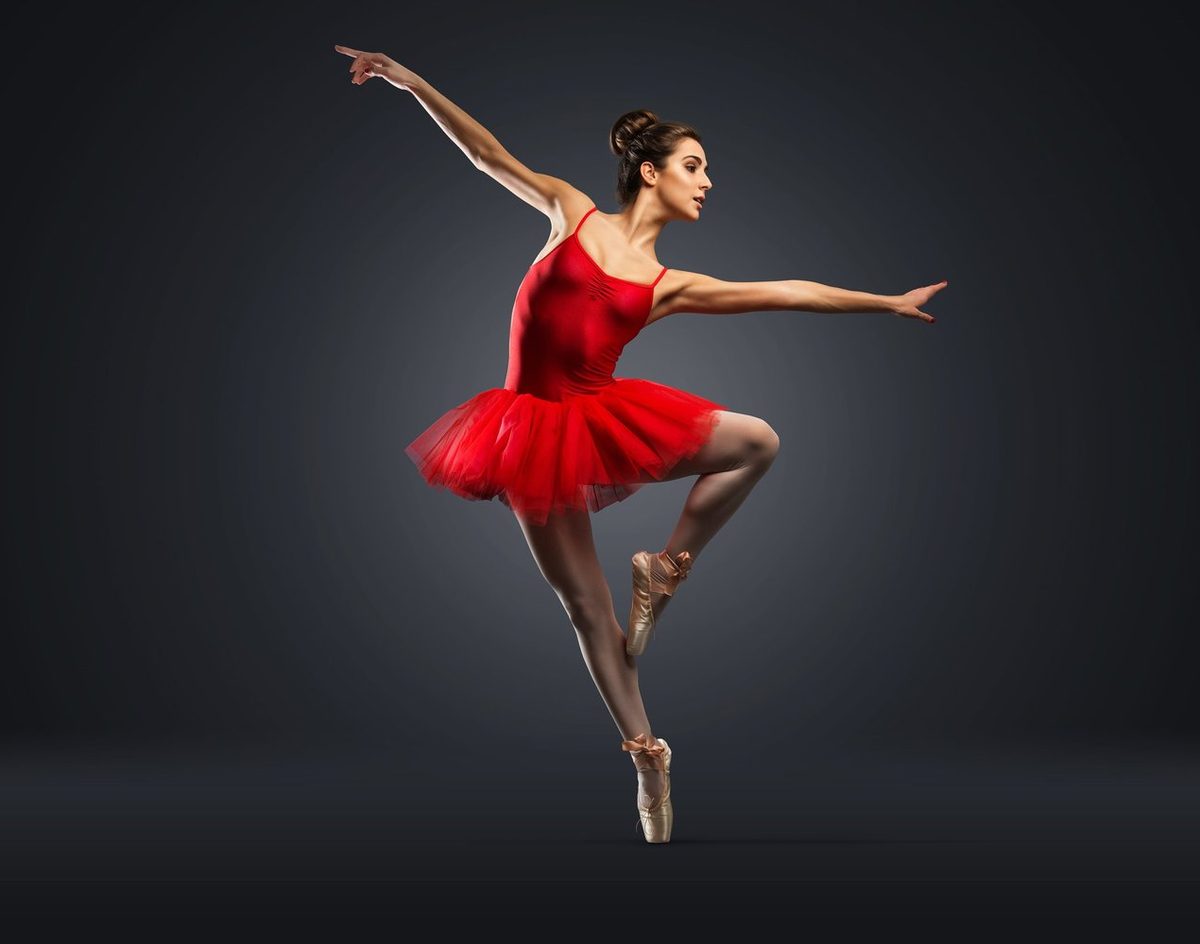 Ballerina in a red dress leaping mid-air
