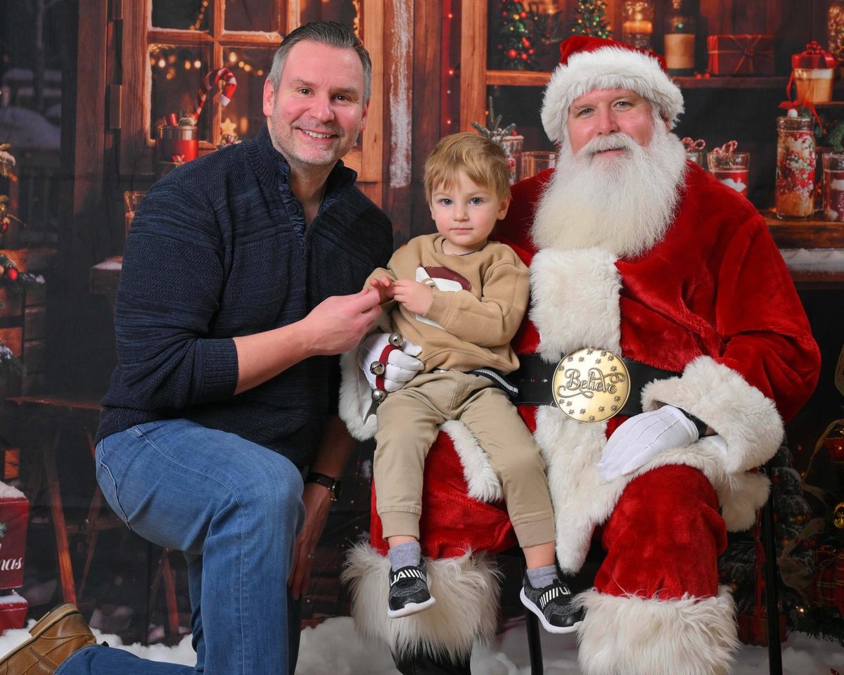 Father and son posing with a real-beard Santa